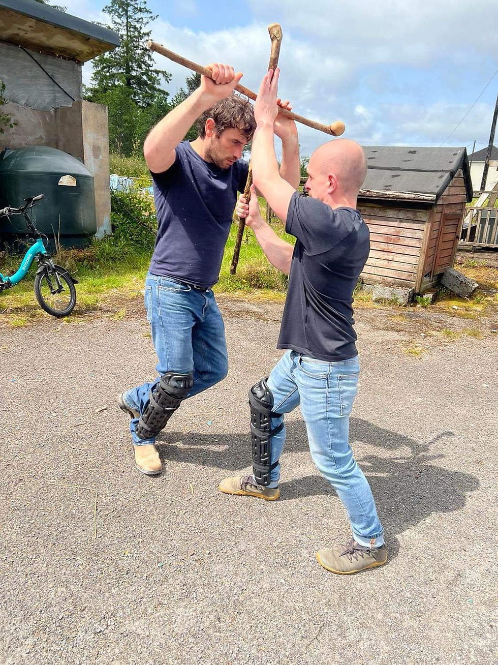 two men clash with wooden sticks