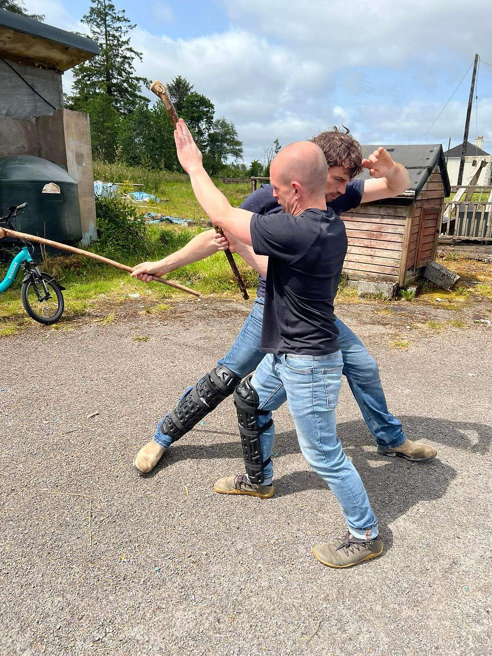 two men fighting with sticks as weapons