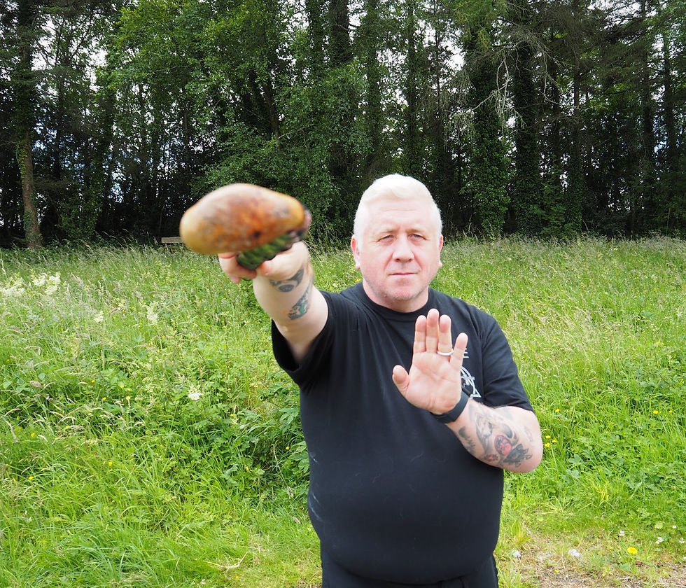 man faces towards the camera with a stick, ready to fight