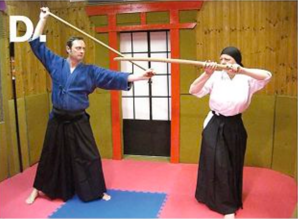 D. The opponent cross-steps backward and raises the bokken to head level, its tip pointing in the direction of the jo practitioner’s head.