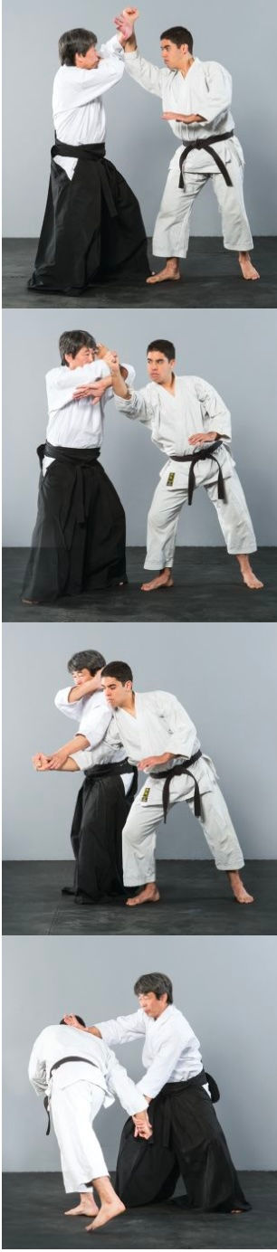 Two people in martial arts uniforms practice Aikido techniques in a gray room. Both display focused expressions, wearing black belts.