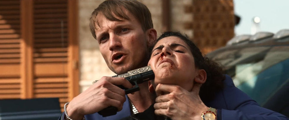 Man holding woman with a gun to her neck, intense expression. Background shows wooden shutters and car, conveying tension and danger.