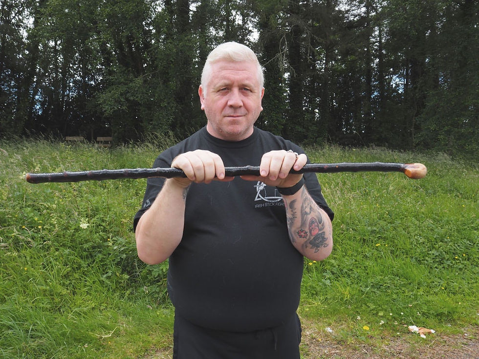 man holds a fighting stick close to his body