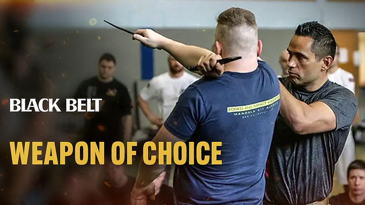 Two men practicing martial arts with weapons in a dojo. Text reads "BLACK BELT WEAPON OF CHOICE." Focused expressions, casual attire.