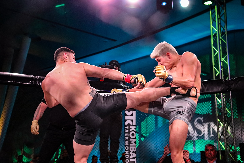 Two fighters in a cage match, one landing a high kick. Bright stage lights, blue and green background. Intense action and focus.