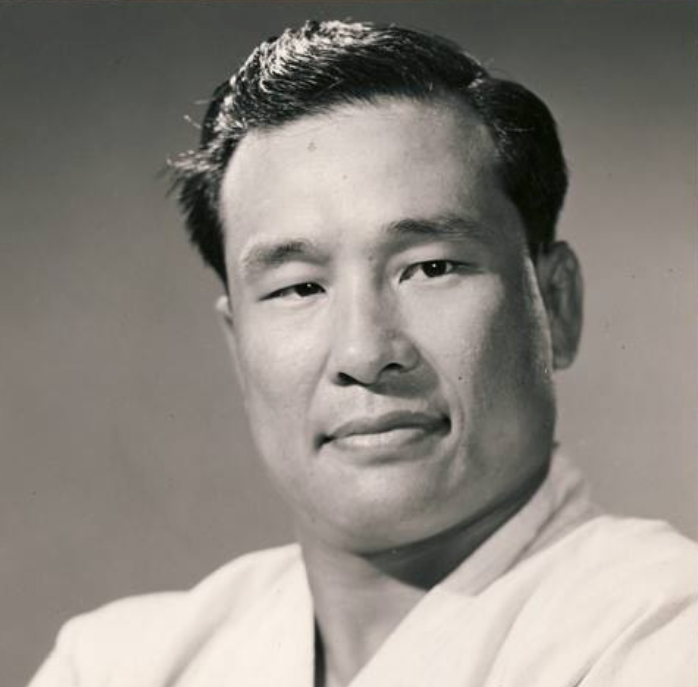 Black-and-white portrait of a person wearing a light-colored gi, showing a calm and confident expression against a plain background.